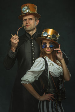 The couple steampunk. A man with a pipe and a girl with glasses