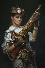 Fototapeta premium Portrait of a beautiful steampunk woman holding a gun