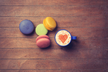 Cup and macarons on wooden background