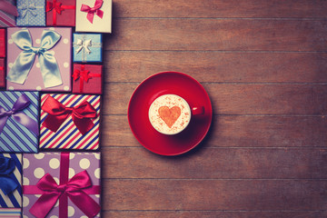 Cup and gift boxes on wooden background