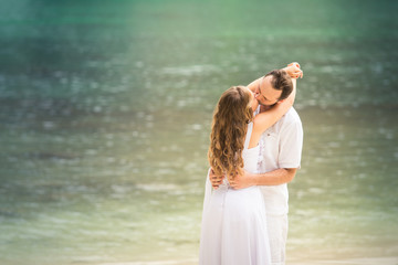 Fototapeta na wymiar blonde bride and groom kiss standing at sand beach