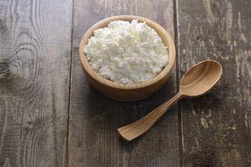 curds in a wooden bowl on a dark wooden background