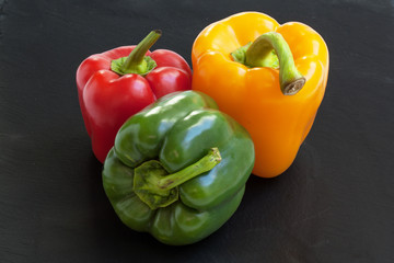 Poivrons de couleurs différentes en gros plan sur ardoise