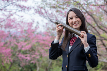 卒業証書の筒を持って笑っている女子学生