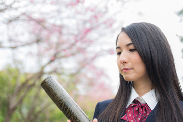 卒業証書の筒を持って笑っている女子学生