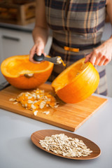 Closeup on seeds and housewife removing filling from pumpkin