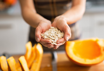 Closeup on young housewife showing pumpkin seeds - obrazy, fototapety, plakaty