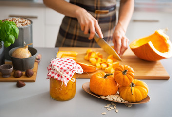Closeup on young housewife cutting pumpkin for pickling - obrazy, fototapety, plakaty