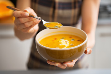Young woman showing pumpkin soup