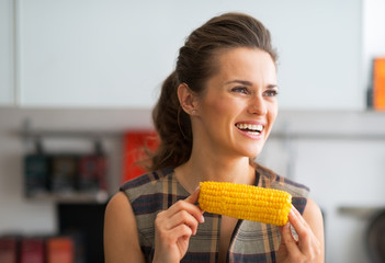 Portrait of happy young housewife eating boiled corn © Alliance