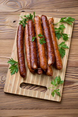 Wooden cutting board with sausages and parsley, high angle view