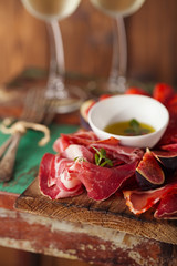Cured Meat and vintage forks on textured Chalkboard and old wood