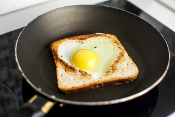 Slice of cereal toast bread with cut out heart shape full egg on