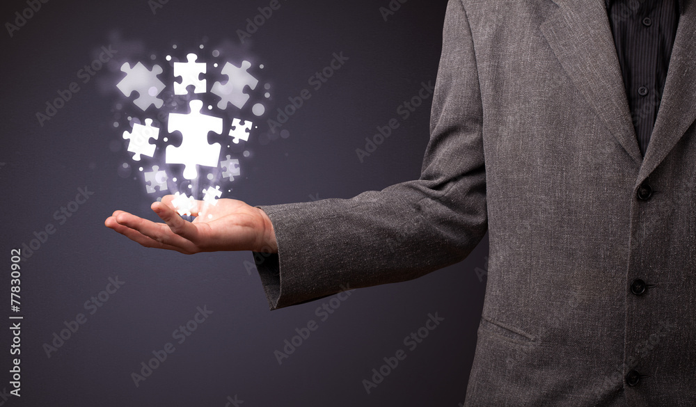 Wall mural Puzzle pieces in the hand of a businessman