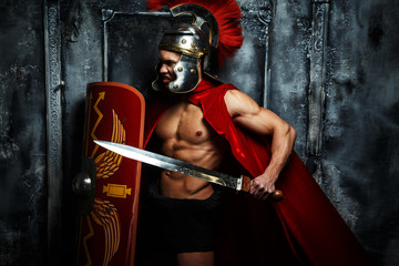 Fototapeta na wymiar Roman warrior with muscular body holding sword and shield