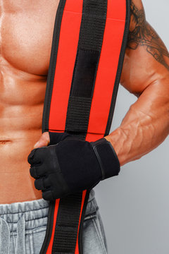 Muscular man showing his abs and holding power-belt