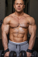 Fototapeta na wymiar Strong muscular man bodybuilder shows his muscles.