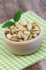 Pistachio nuts in wooden bowl on checkered cloth