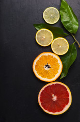 Fototapeta na wymiar Set of sliced citrus fruits over black texture.Top view
