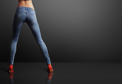 perfect shaped woman wearing skinny jeans in a dark room