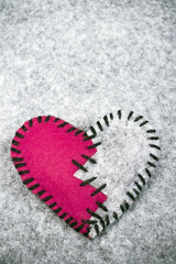 stitched broken felt heart on a on a gray background
