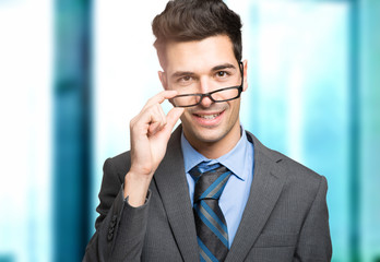 Confident smiling young manager holding his glasses