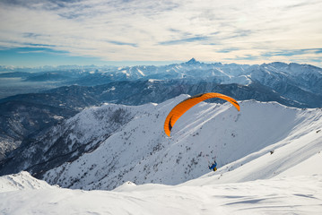 Paraglider launching from snowy slope