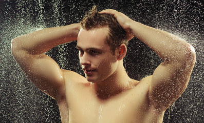 Handsome young man taking a shower