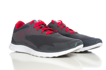 A pair of gray running shoes with red shoelaces on a white backg