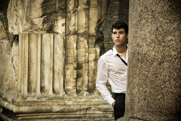 Handsome young man between ancient marble columns