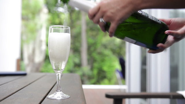 Woman pours bubbly champagne into a champagn flute glass