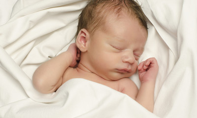New born baby boy sleeping. Baby taking a nap in white sheets.