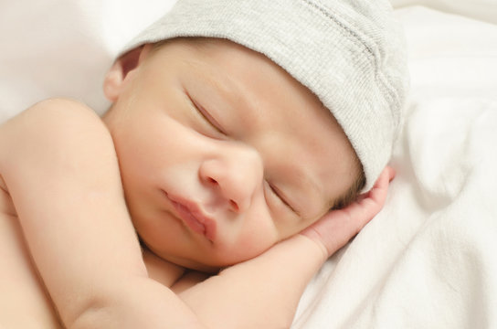 New born baby boy with cute gray hat sleeping taking a nap.
