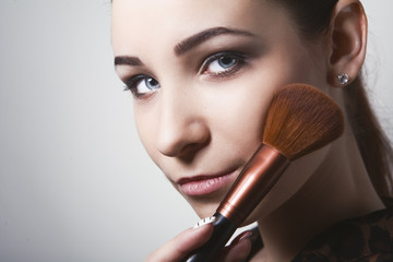 young woman holding different make-up brushes.