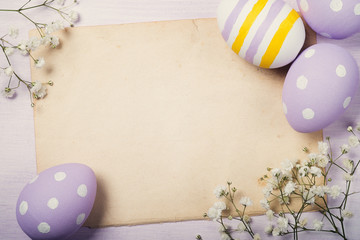 Colorful Easter eggs and flowers on old sheet of paper with spac