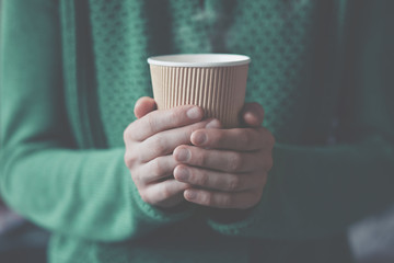 hands holding paper cup with take-out coffee