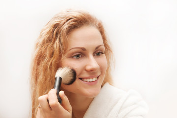 Attractive woman doing make-up on face.