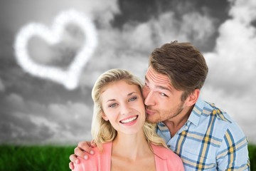 Fototapeta premium Composite image of handsome man kissing girlfriend on cheek