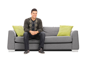 Cheerful young man sitting on a modern sofa