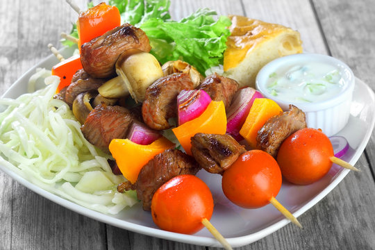 Kebabs on Plate with Mustard, Veggies and Bread