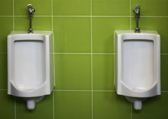 Urinals on green wall