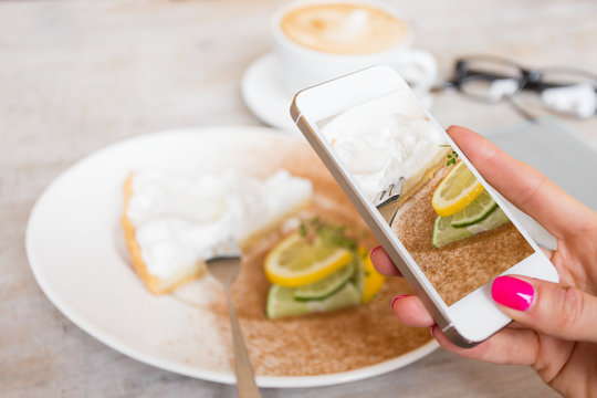 Woman taking food photo in cafe with mobile phone