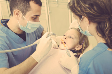 Dentist and Dental Assistant examining Young Girl teeth.