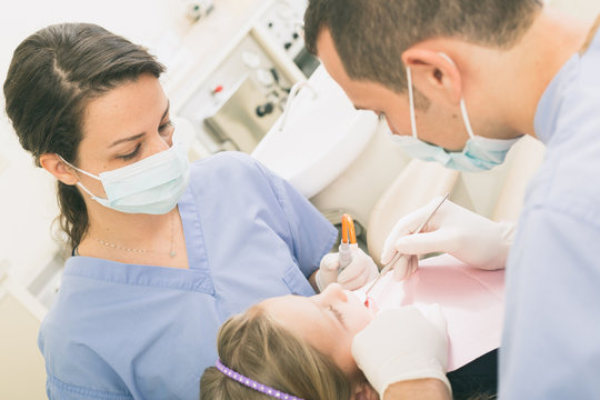 Dentist and Dental Assistant examining Young Girl teeth.