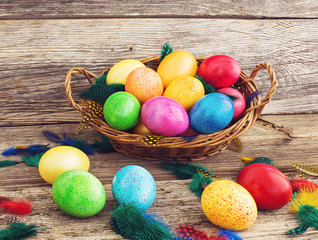 Colorful Easter eggs in basket on wooden background