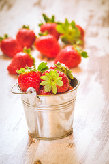 Spring fruits, strawberries in an aluminum bucket on a vintage w