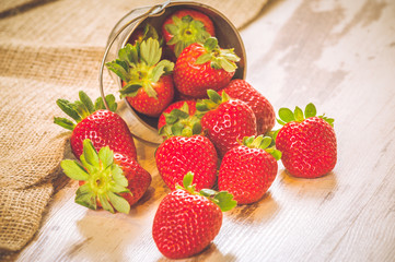 Spring fruits, strawberries in an aluminum bucket on a vintage w