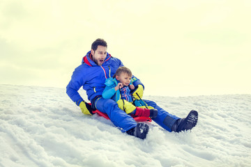 Fototapeta na wymiar little boy and his father sledding very fast,