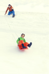 Fototapeta na wymiar little boy sledding very fast pushed by his father