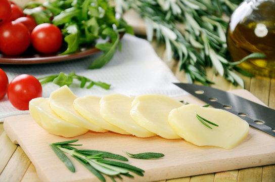 sliced cheese, tomatoes and herbs on a kitchen table closeup